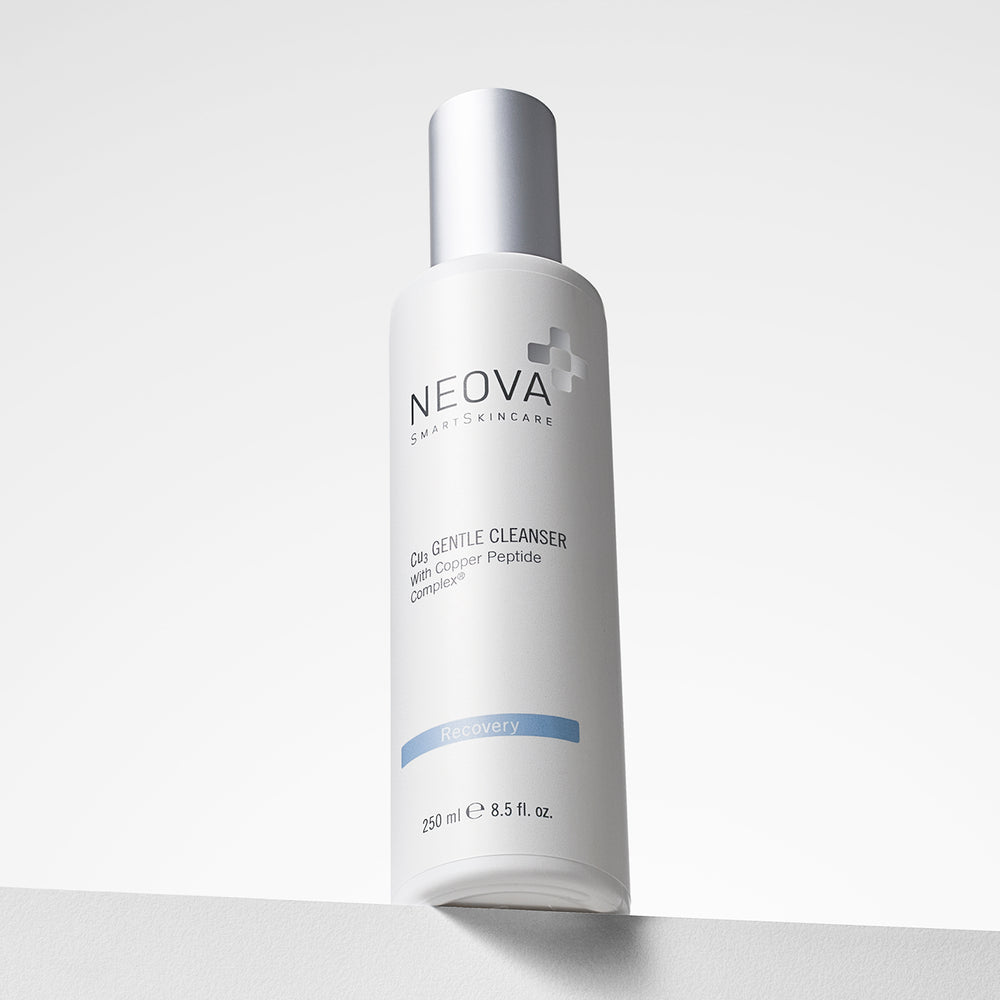 A white bottle of NEOVA Smart Skincare Cu3 Gentle Cleanser with a metallic silver cap, standing on a light gray surface against a white background. Neova Cu3 Gentle Cleanser—cream-to-foam gentle face wash for sensitive, post-procedure skin.