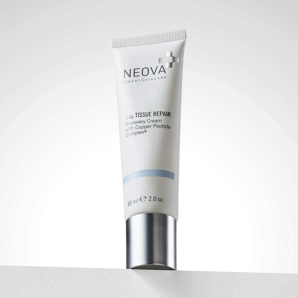A white cosmetic tube of NEOVA Smart Skin Clg Tissue Repair recovery cream with a metallic silver cap, standing upright on a light gray surface against a white background. NEOVA Cu3 Tissue Repair cream on a clean background, intensive post-procedure recovery cream with copper peptides.
