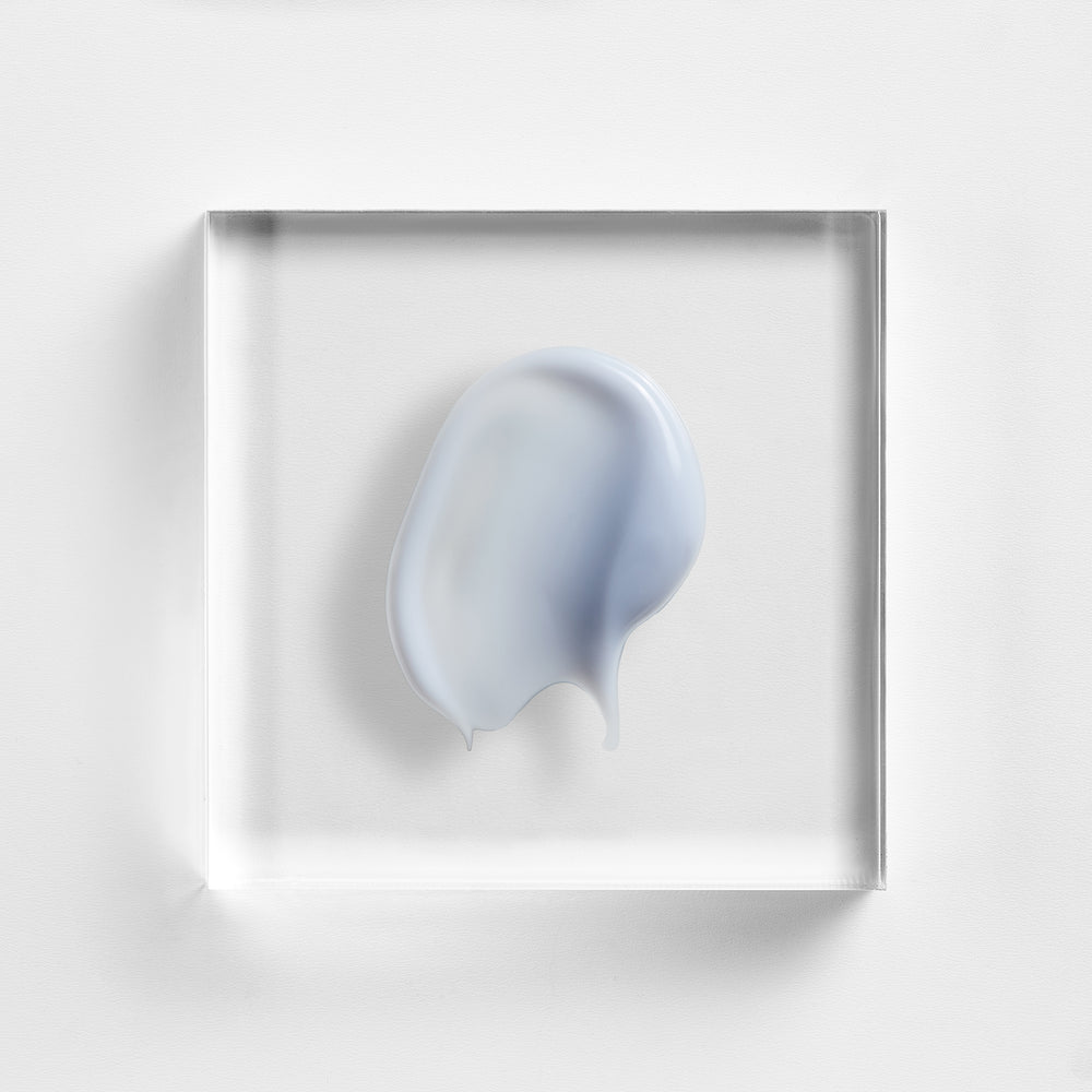 Abstract light blue shape in a clear rectangular frame on a white background. Close-up of NEOVA Illuminating Eye Balm texture, lightweight eye treatment for brighter, smoother-looking skin.