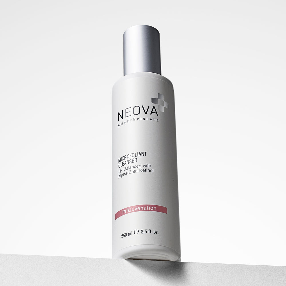 A white bottle of Neova Smart Skincare Microfoliant Cleanser with a metallic silver cap, standing on a light gray surface against a white background. NEOVA Microfoliant Cleanser bottle on a clean background, exfoliating cleanser for pores and uneven texture.