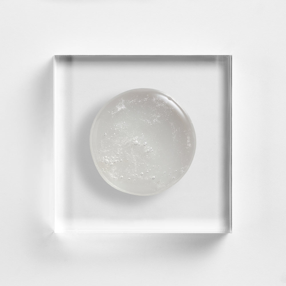 Round texture in a clear square frame on a white background. Close-up texture of NEOVA Microfoliant Cleanser, alpha-beta-retinol cleansing gel with salicylic acid and retinol.