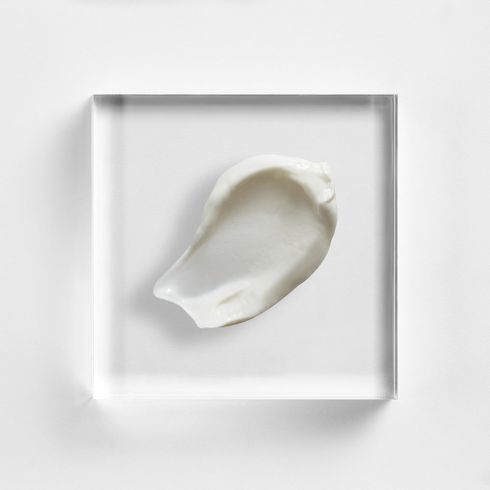 White cream sample in a clear square container on a light gray background. Close-up texture of NEOVA Multi-Active Day Cream, treatment moisturiser with AHA, BHA and green tea extract.