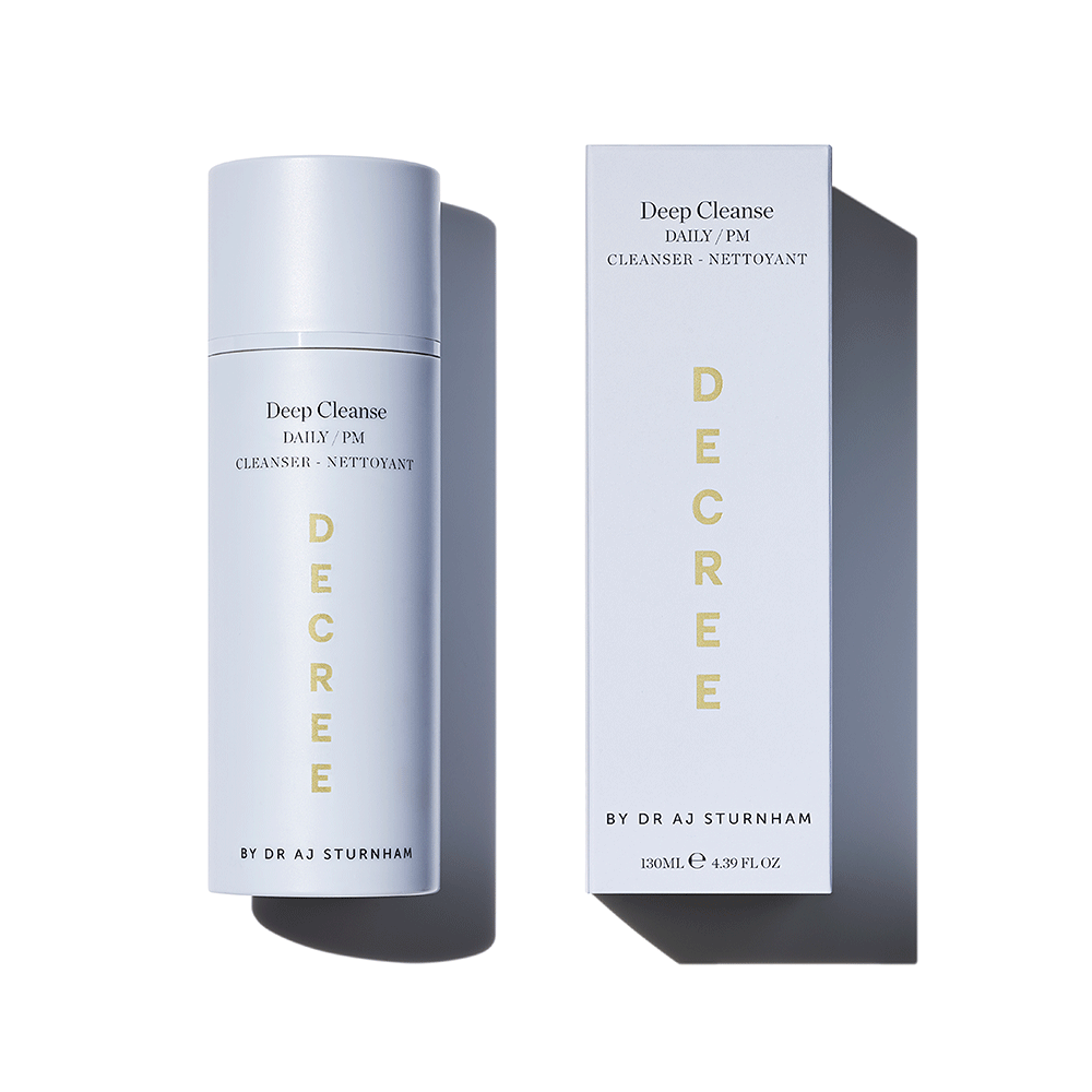 A skincare product bottle and its matching outer box on a clean white background. The bottle and box are a very pale icy blue with gold vertical lettering spelling 'DECRE' and black text reading 'Deep Cleanse' and 'Cleanser'.