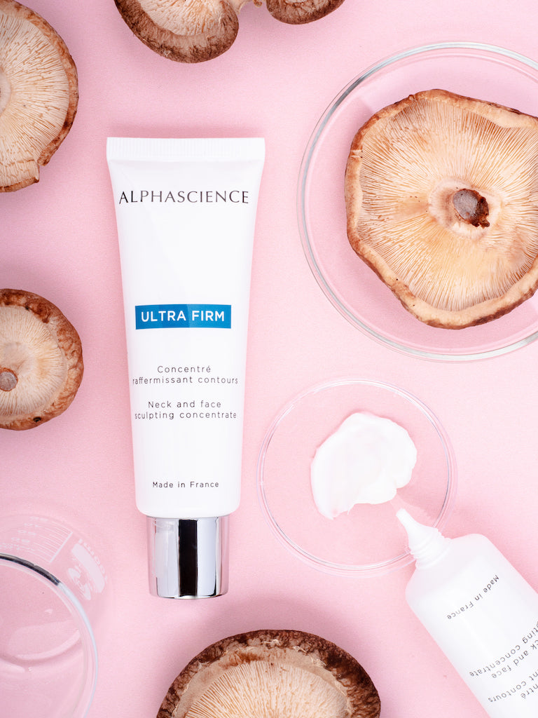 Ultra Firm texture by Alphascience—silky, matte finish cream that smooths aging skin on a pink background with dried mushrooms.