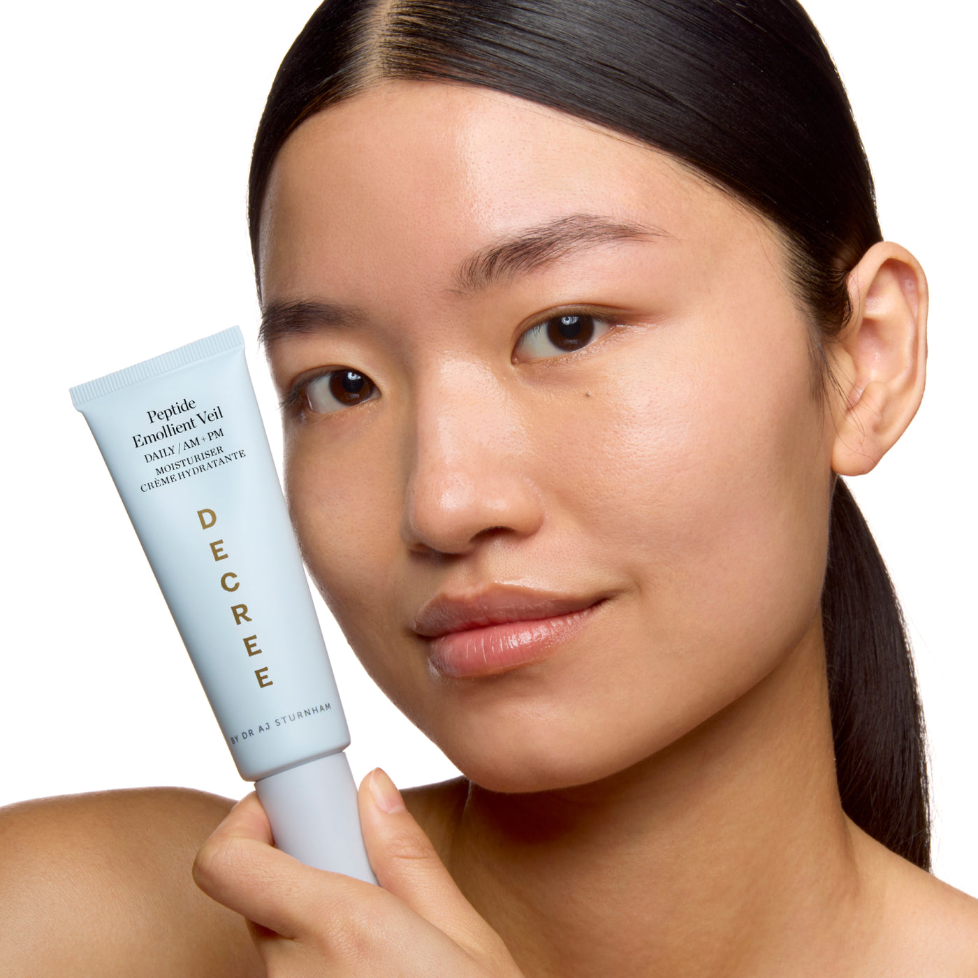 Woman holding a skincare product with 'Decree' branding on a white background