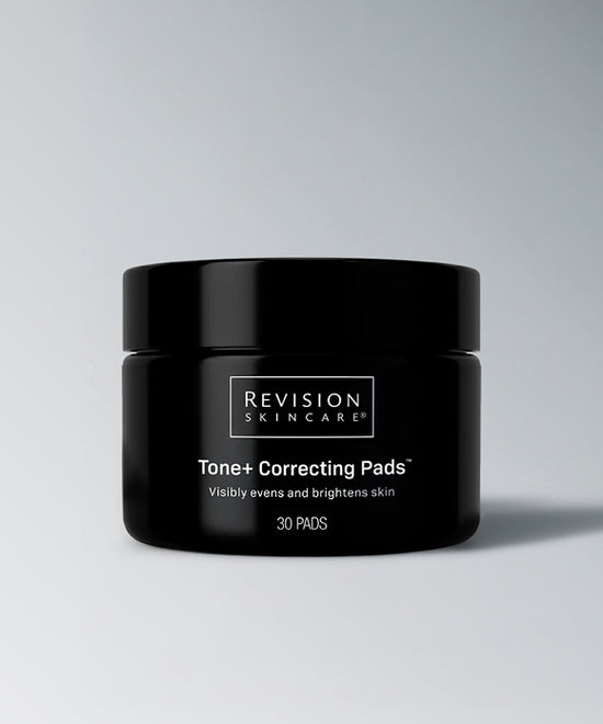 A black cosmetic jar of Revision Skincare Tone+ Correcting Pads on a light gray background. Revision Skincare Tone+ Correcting Pads™ for dullness, uneven tone, discoloration, rough texture, and visible pores.