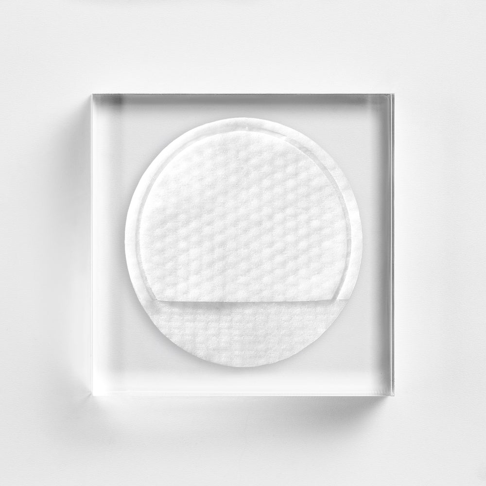White round cotton pad in a clear plastic case on a white background. Close-up of a NEOVA 5-Second Daily Peel pad, a one-step treatment for dullness, uneven tone, and visible pores.