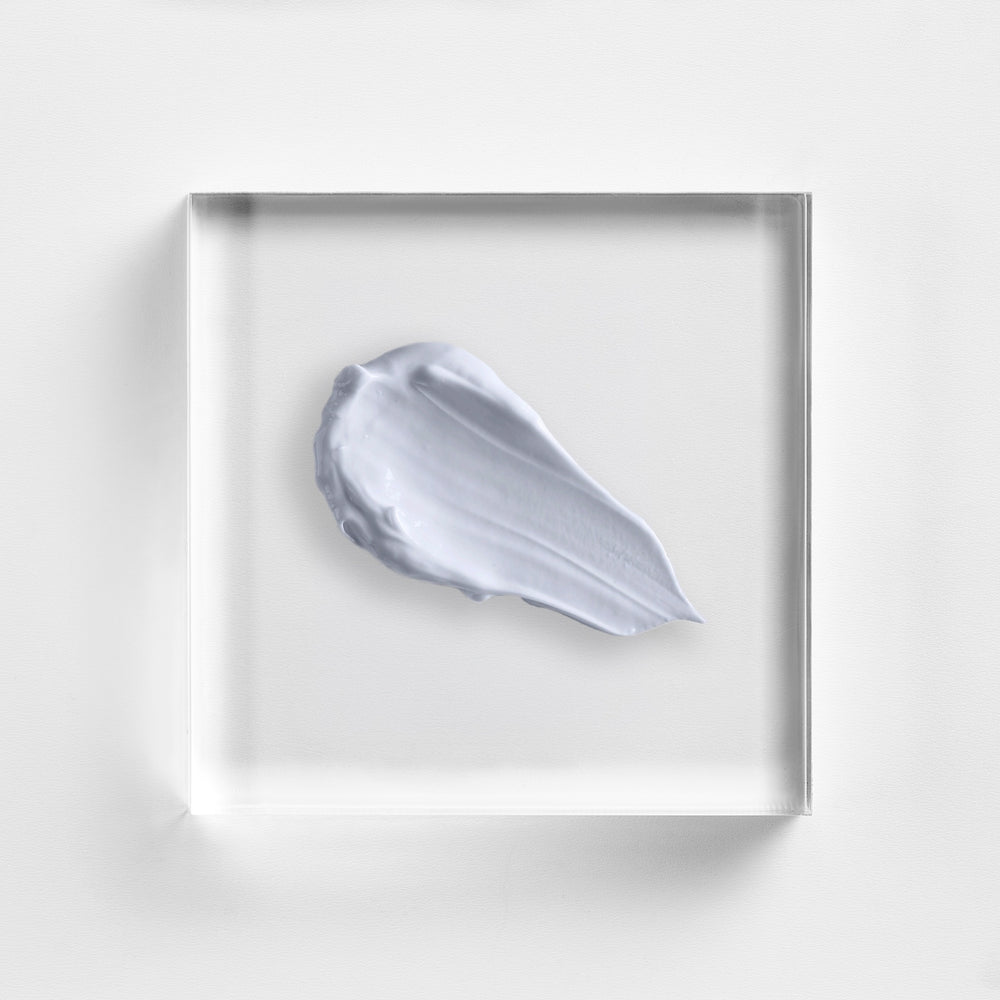 White cream swatch on a clear square platform with a white background. Close-up of NEOVA Cu3 Recovery Lotion’s mid-weight texture, designed to lock in moisture and help prevent scabbing.