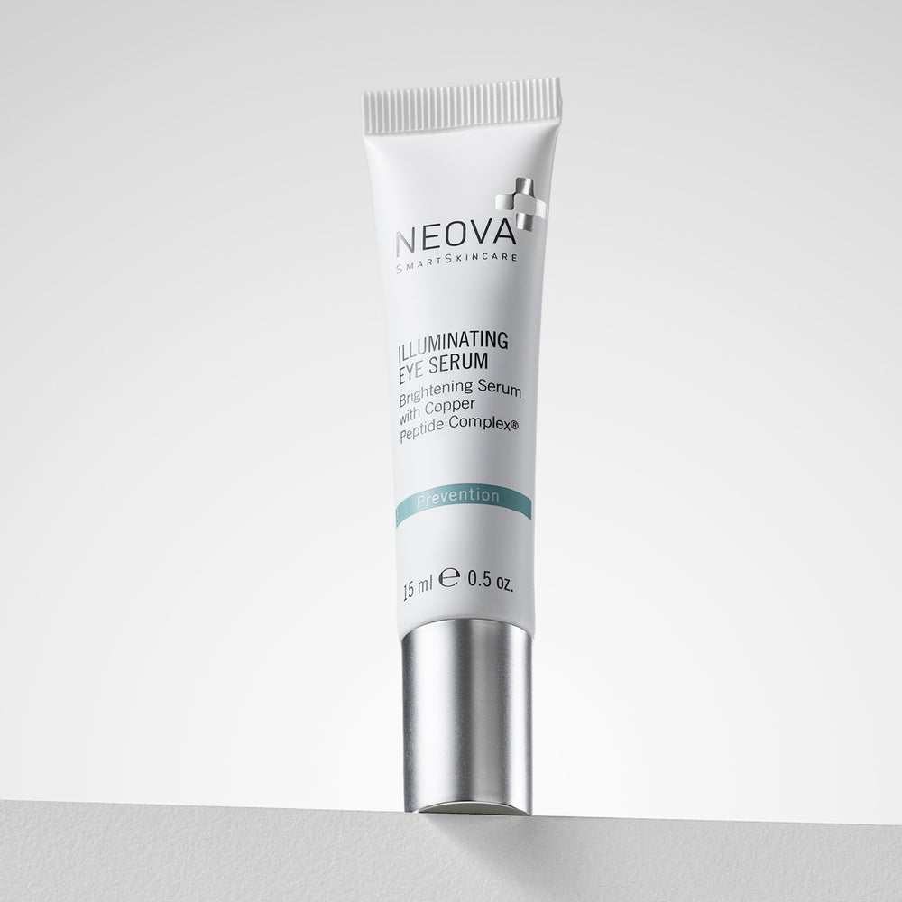 A 25 ml white squeeze tube of NEOVA Cosmetics Illuminating Eye Serum with a metallic silver cap, standing upright on a light gray surface against a neutral light gray background. NEOVA Illuminating Eye Balm on a clean background, brightening eye treatment for dark circles and puffiness.